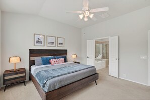 A bedroom with a bed, nightstands, a ceiling fan, and a bathroom with a shower and mirror. - Family friendly w/ beautiful pool, SPA, and BBQ terrace! (Tomball)