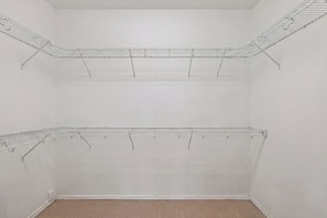 A closet with two metal wire shelves, a beige carpet, and white walls. - Family friendly w/ beautiful pool, SPA, and BBQ terrace! (Tomball)