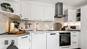 A modern kitchen with white cabinets, a stainless steel range hood, a dishwasher, and a microwave.
