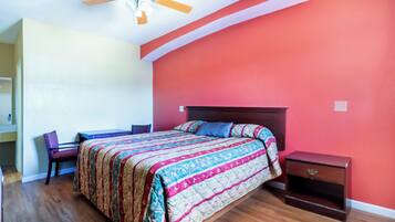 A bedroom with a bed, a desk, and a nightstand.