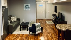 A modern living room with a grey sofa, a coffee table, and a TV on a wooden floor.