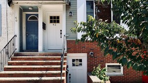 A two-story building with a white front door, a small porch, and a brick exterior.