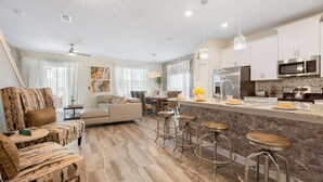 A modern kitchen with a central island, bar stools, and stainless steel appliances.