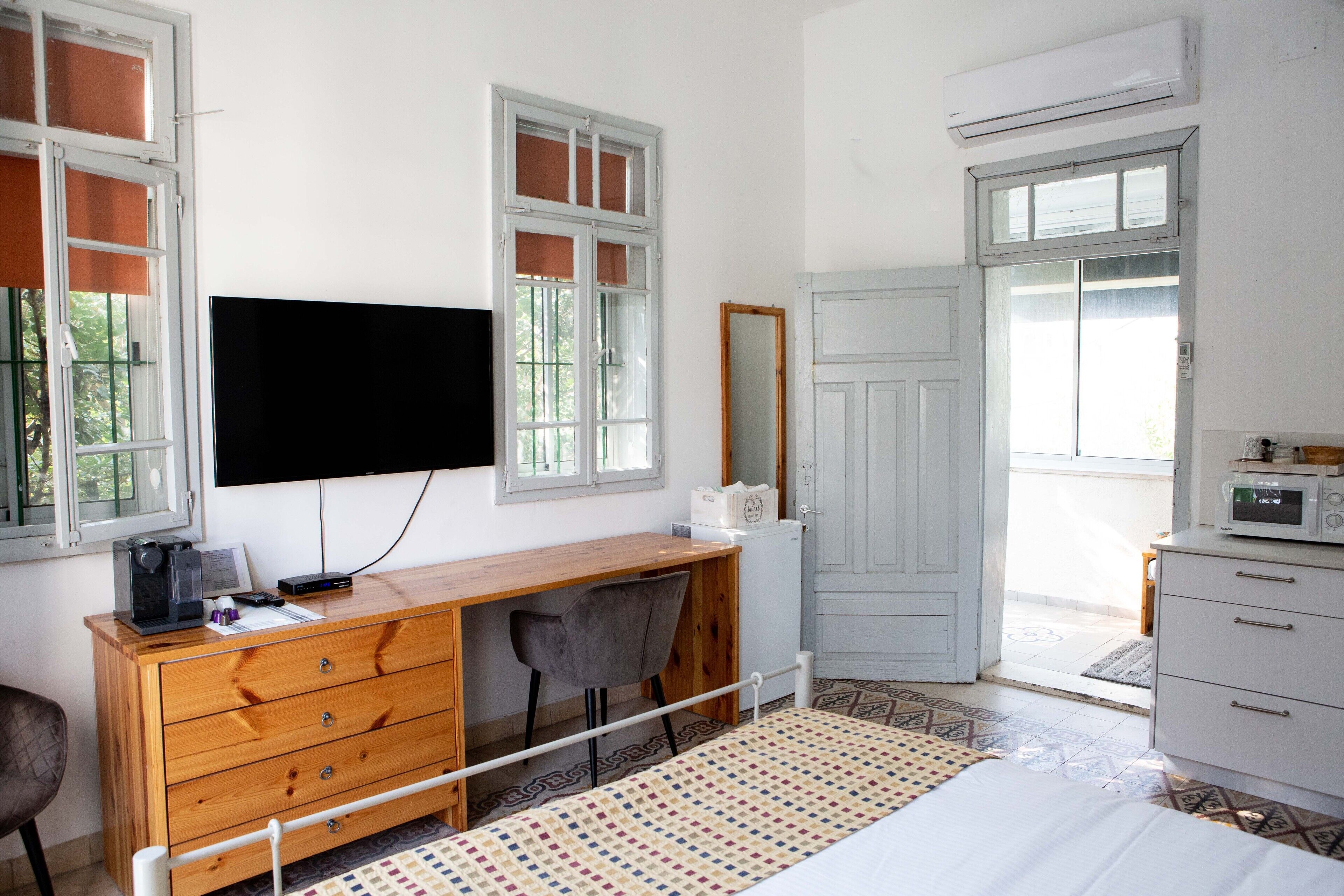 Camera da letto con un letto, una scrivania, una sedia, una televisione, un armadio e una finestra.