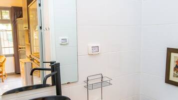 A compact bathroom with a black sink, a toilet, and a mirror.
