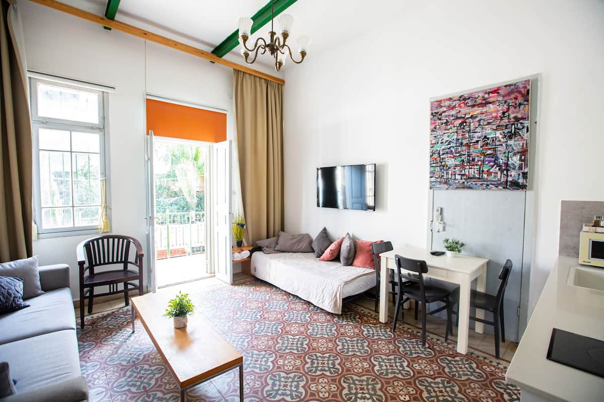 Een moderne woonkamer met een bank, een eettafel en een aan de muur bevestigde televisie.