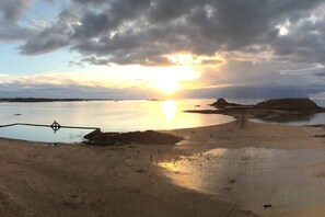 A beach with a calm sea, a sunset, and a compass in the foreground.