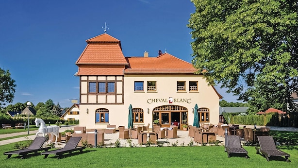 Ein zweistöckiges Gebäude mit dem Schriftzug 'CHEVAL BLANC'.