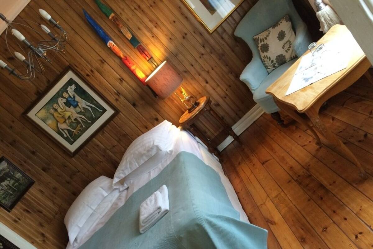 Une pièce aux murs lambrissés, avec un lit, une table et une lampe.