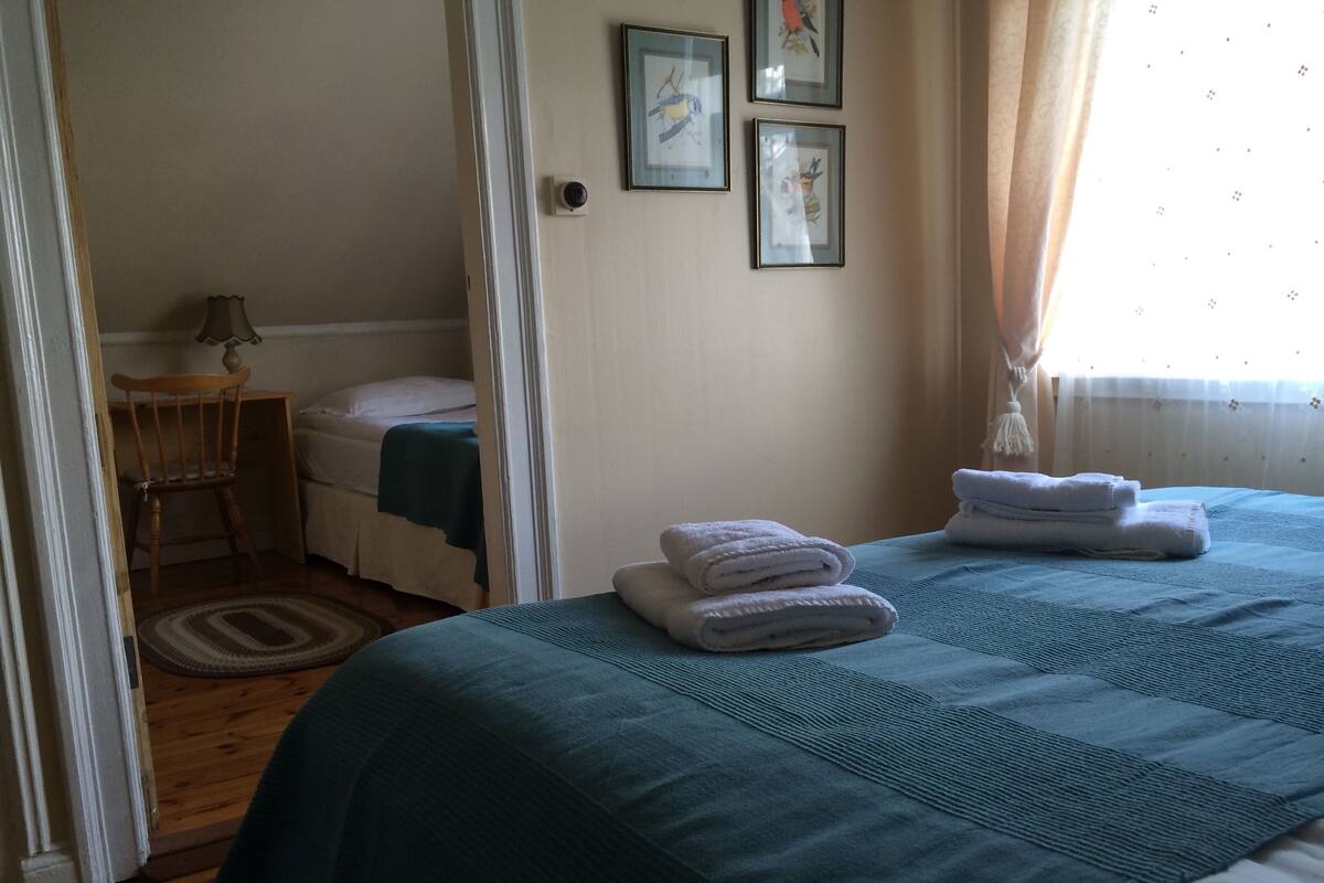 Une chambre à coucher avec un lit, une chaise, un bureau et une fenêtre avec des rideaux.
