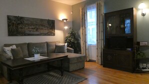 Een woonkamer met een bank, een salontafel, een televisie en een schilderij aan de muur.