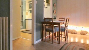 Een eetgedeelte met een tafel, stoelen, een kleine plant in pot en een wandklok.