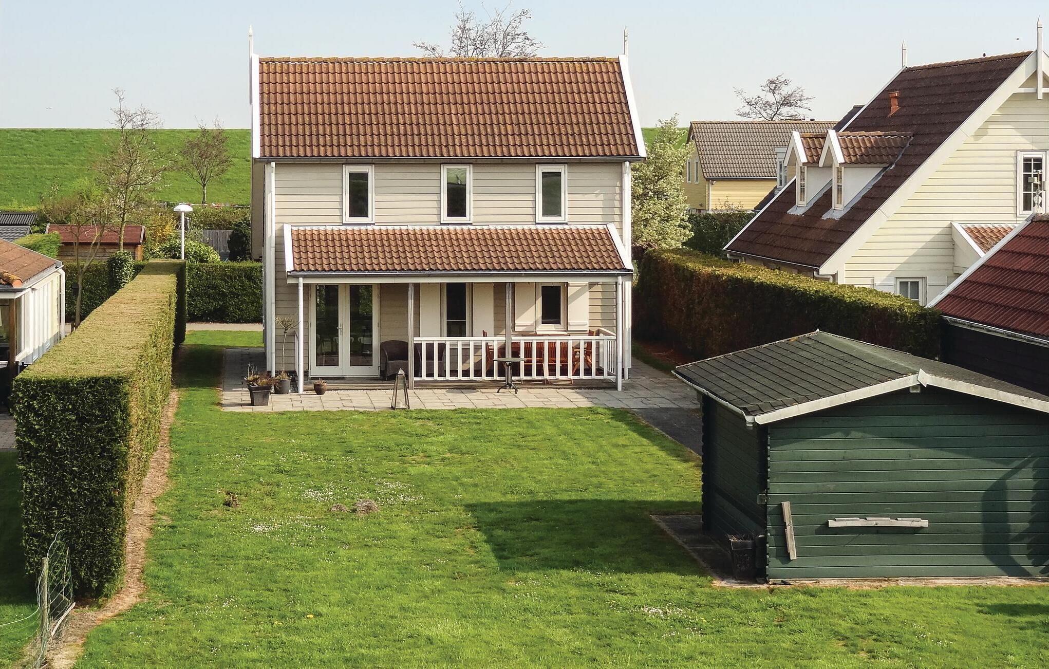 A two-story house with a covered porch and a green shed in the backyard.