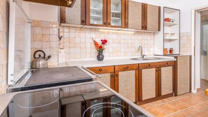 A kitchen with a stove, sink, and wooden cabinets.