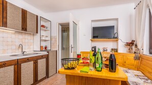 A kitchen with a wooden island, a built-in sink, and a television above the counter.