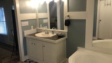 A bathroom with a white sink, a large mirror, and a bathtub.