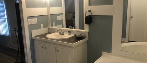 Un baño con lavamanos blanco, un espejo grande y una bañera.
