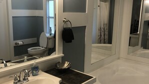 Un baño con un lavabo blanco, un espejo grande, un inodoro y una bañera.