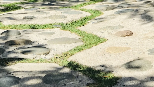 A pathway with a patterned stone design, surrounded by greenery and a wooden structure. - Lagi 1001 Nights Hotel (La Gi)