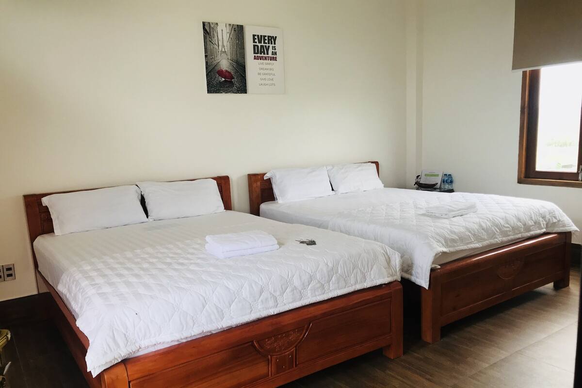 A hotel room with two wooden beds, white bedding, and a poster on the wall.