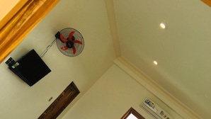 A room with a bed, a wall-mounted fan, an air conditioning unit, and a wooden door. - Lagi 1001 Nights Hotel (La Gi)