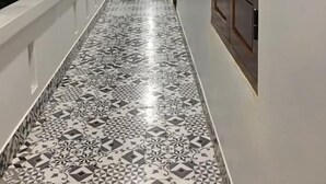 A corridor with patterned flooring, white walls, and wooden doors. - Lagi 1001 Nights Hotel (La Gi)