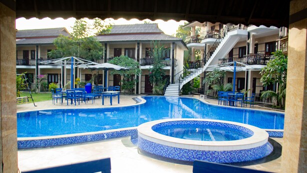 A pool area with a hot tub, lounge chairs, and a staircase leading to an upper level.