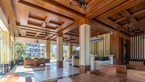 A spacious lobby with wooden flooring, high ceilings, and a reception desk.