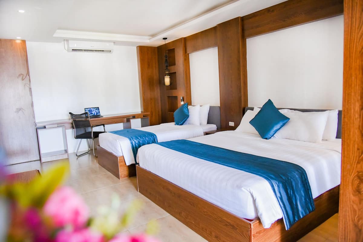 Quarto de hotel com duas camas, uma escrivaninha e uma cadeira.