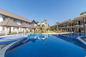 A swimming pool surrounded by buildings with balconies and a clear sky. - Diamond Resort Vang Vieng (Vang Vieng)