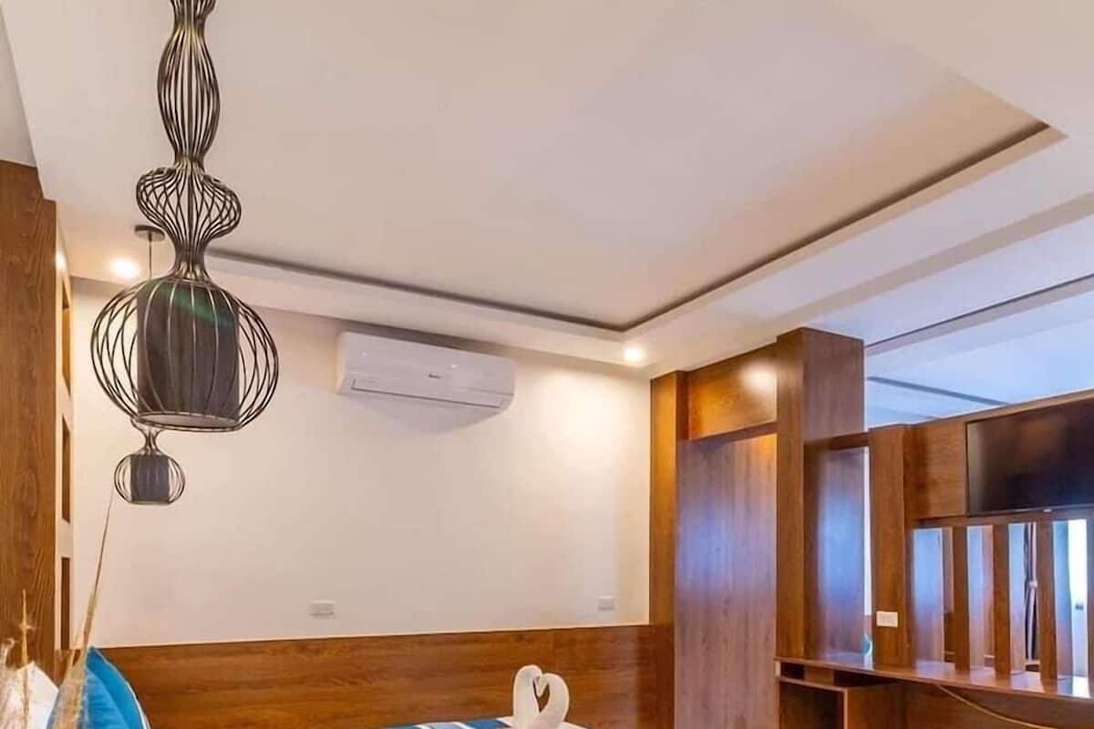 Quarto de hotel moderno com uma cama grande, um móvel decorativo e um candelabro único.