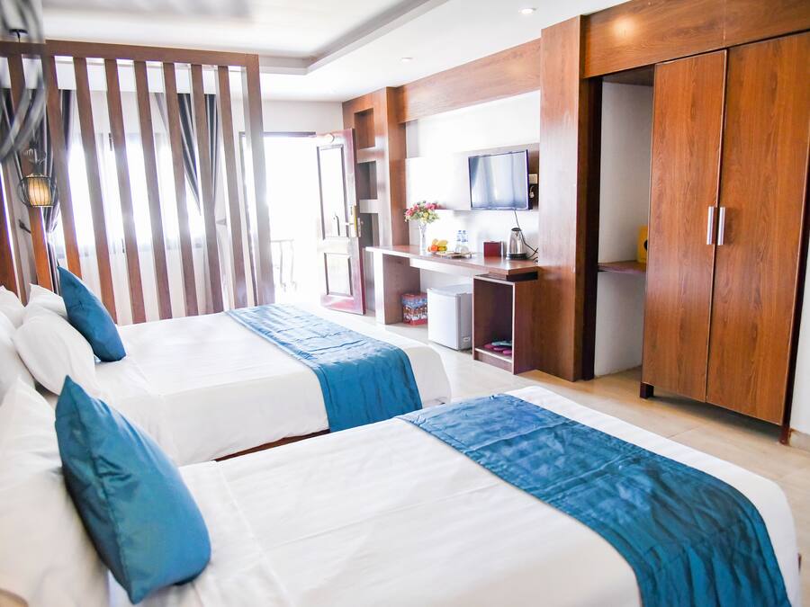 Una habitación de hotel con dos camas, televisión, escritorio y armario.