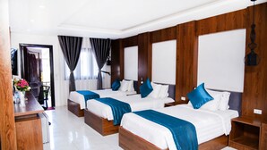 A hotel room with three beds, a desk, and a chair.