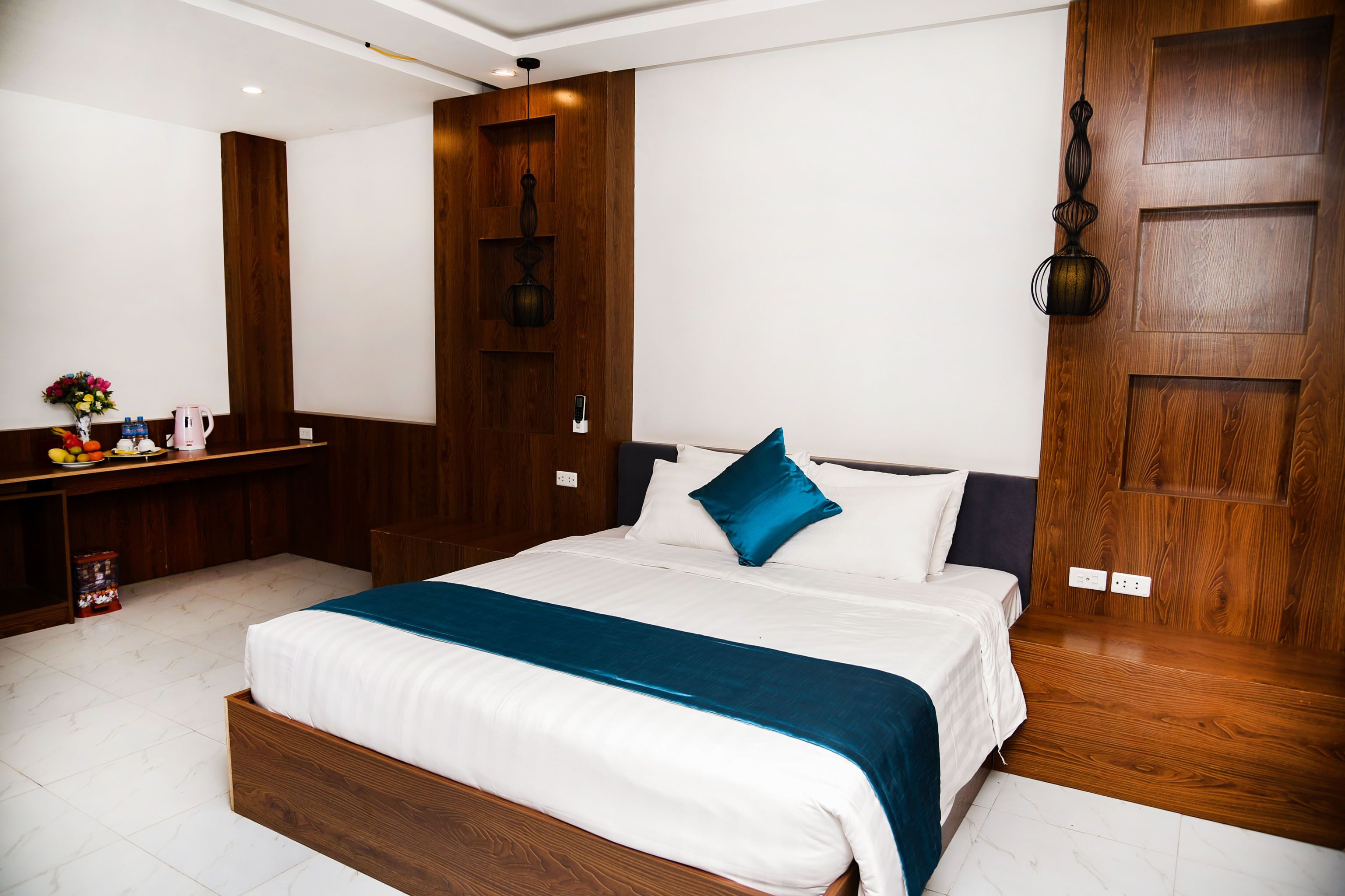 Une chambre moderne avec un cadre de lit en bois, une literie blanche et un coussin décoratif bleu.