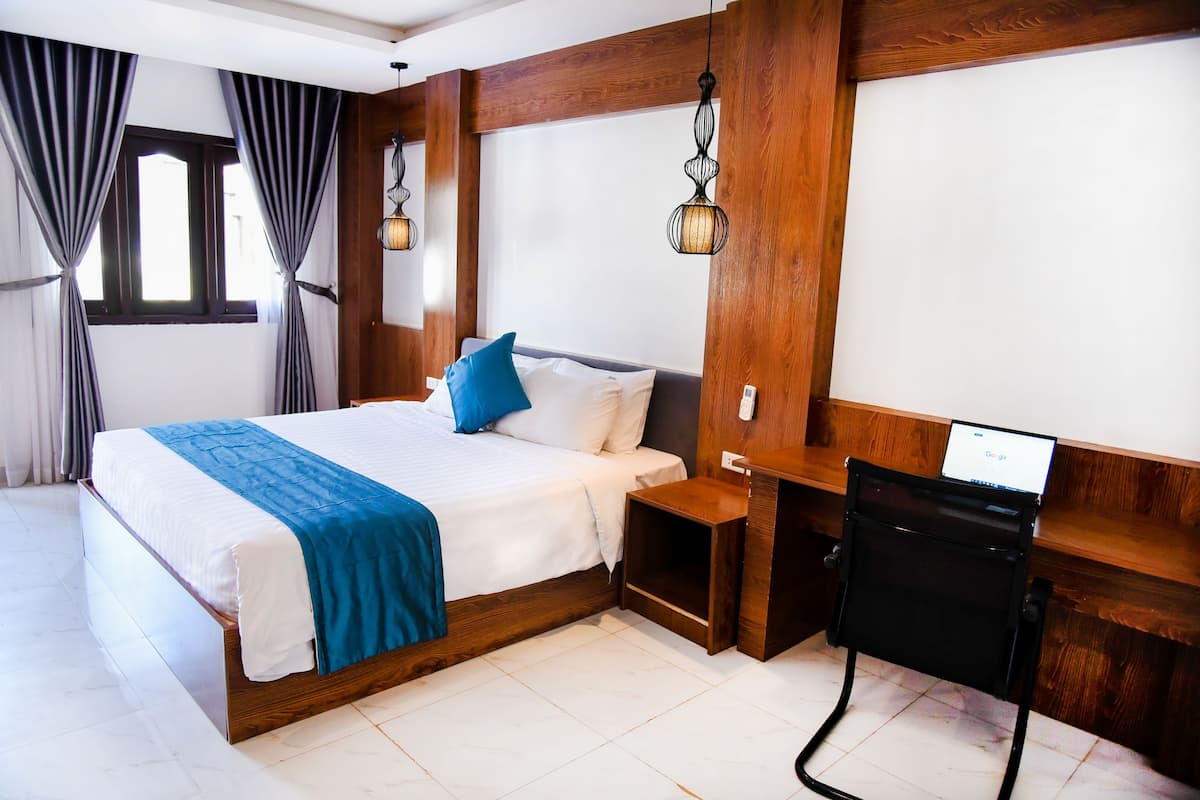 Quarto de hotel com cama, escrivaninha e cadeira.