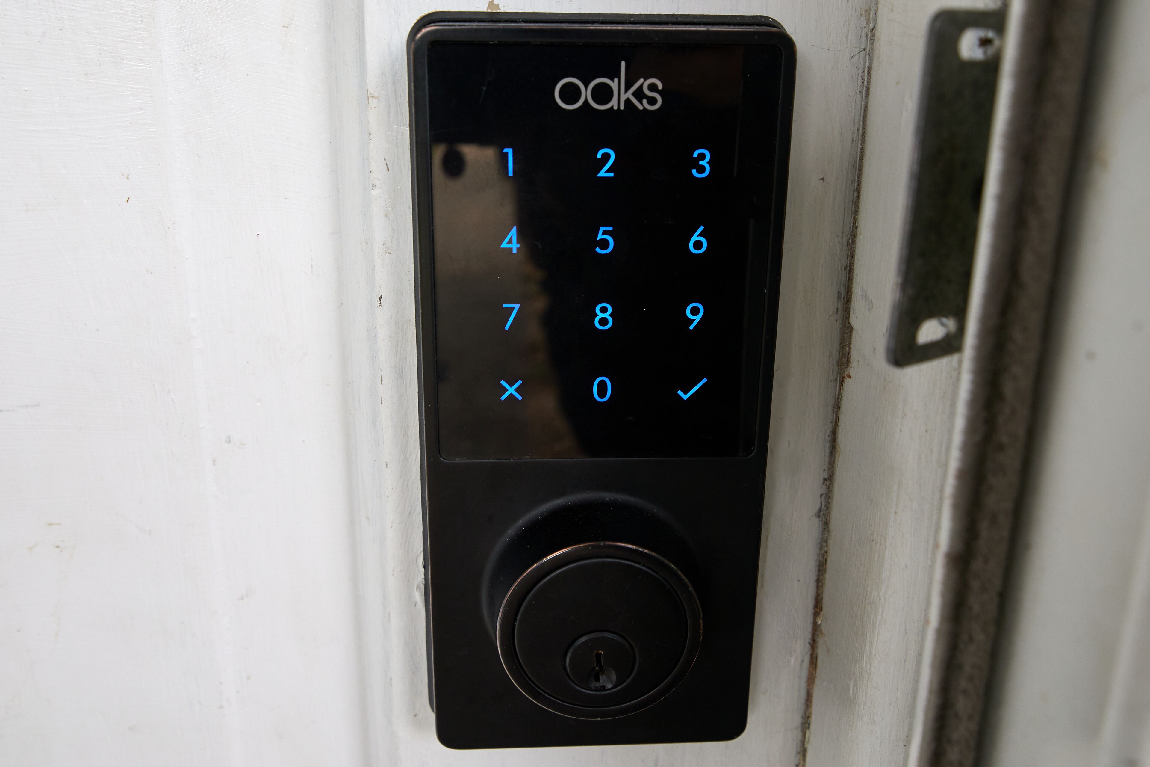 Uma fechadura eletrônica preta em uma porta branca.