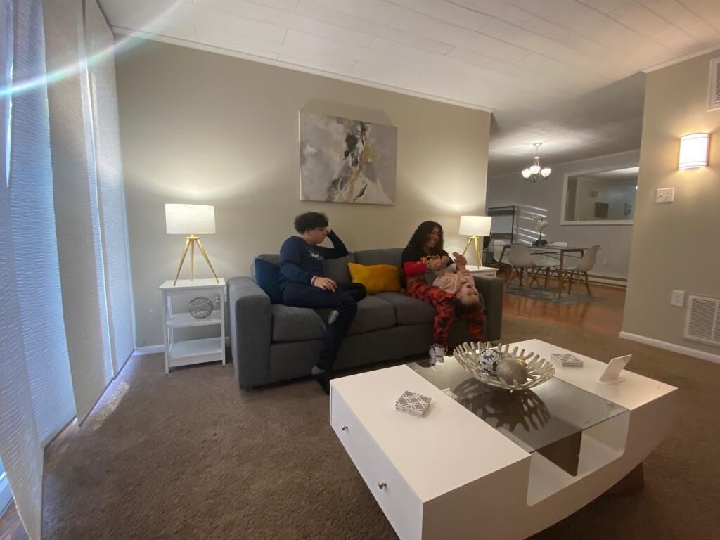 A living room with a grey sofa, a white coffee table, and a painting on the wall.