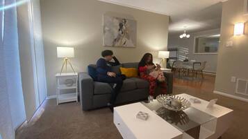 A living room with a grey sofa, a white coffee table, and a painting on the wall.