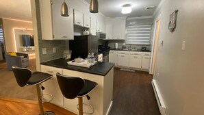 A modern kitchen with white cabinets, a black countertop, and two bar stools. - Close to lot of shopping areas, eateries, bars and more. Ideal for monthly stays (Lancaster)