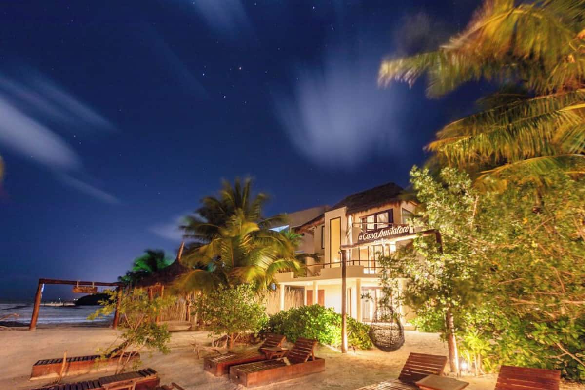 Un hotel frente a la playa con piscina, palmeras y un letrero que dice "Casa Blanca".
