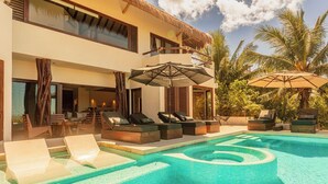 A poolside area with lounge chairs, umbrellas, and a clear view of the pool. - Casa Punta Coco & Beach Club (Isla Holbox)