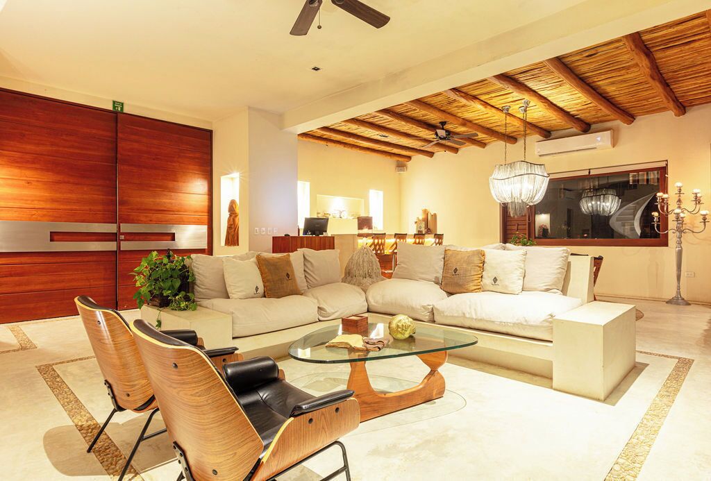 A modern living room with a sectional sofa, a glass coffee table, and wooden chairs.