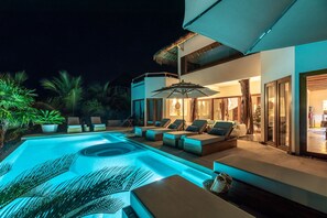 Un espace piscine extérieur moderne, doté de chaises longues et d’un jacuzzi, le tout agrémenté de plantes en pot.