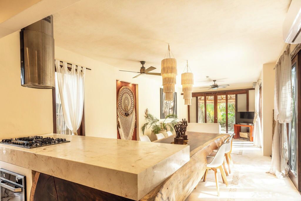 A kitchen with a large island, a ceiling fan, and a view of the outdoors.