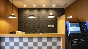 Una recepción con diseño de cuadros, dos lámparas colgantes y una pantalla digital que muestra 