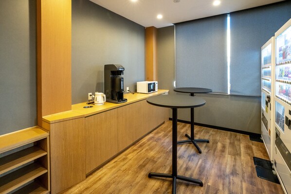 A compact kitchen with a coffee maker, microwave, and a small table.