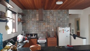 Une cuisine avec un mur recouvert de carreaux décoratifs, un plafond en bois et un réfrigérateur.