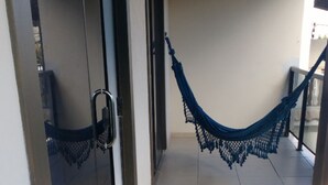 Un couloir avec un hamac suspendu au plafond, une porte vitrée sur la gauche et un sol carrelé.