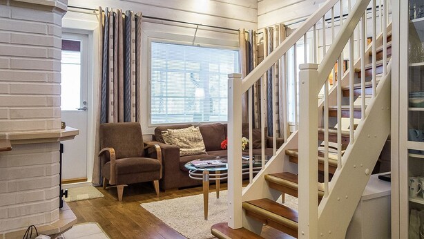 A cozy living room with a fireplace, a sofa, a coffee table, and a staircase. - Lepolinna b by Interhome (Nilsiä)