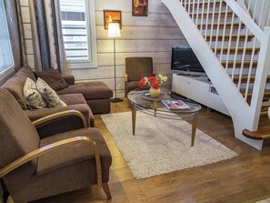 A living room with a sofa set, a coffee table with flowers, a television, and a staircase. - Lepolinna b by Interhome (Nilsiä)